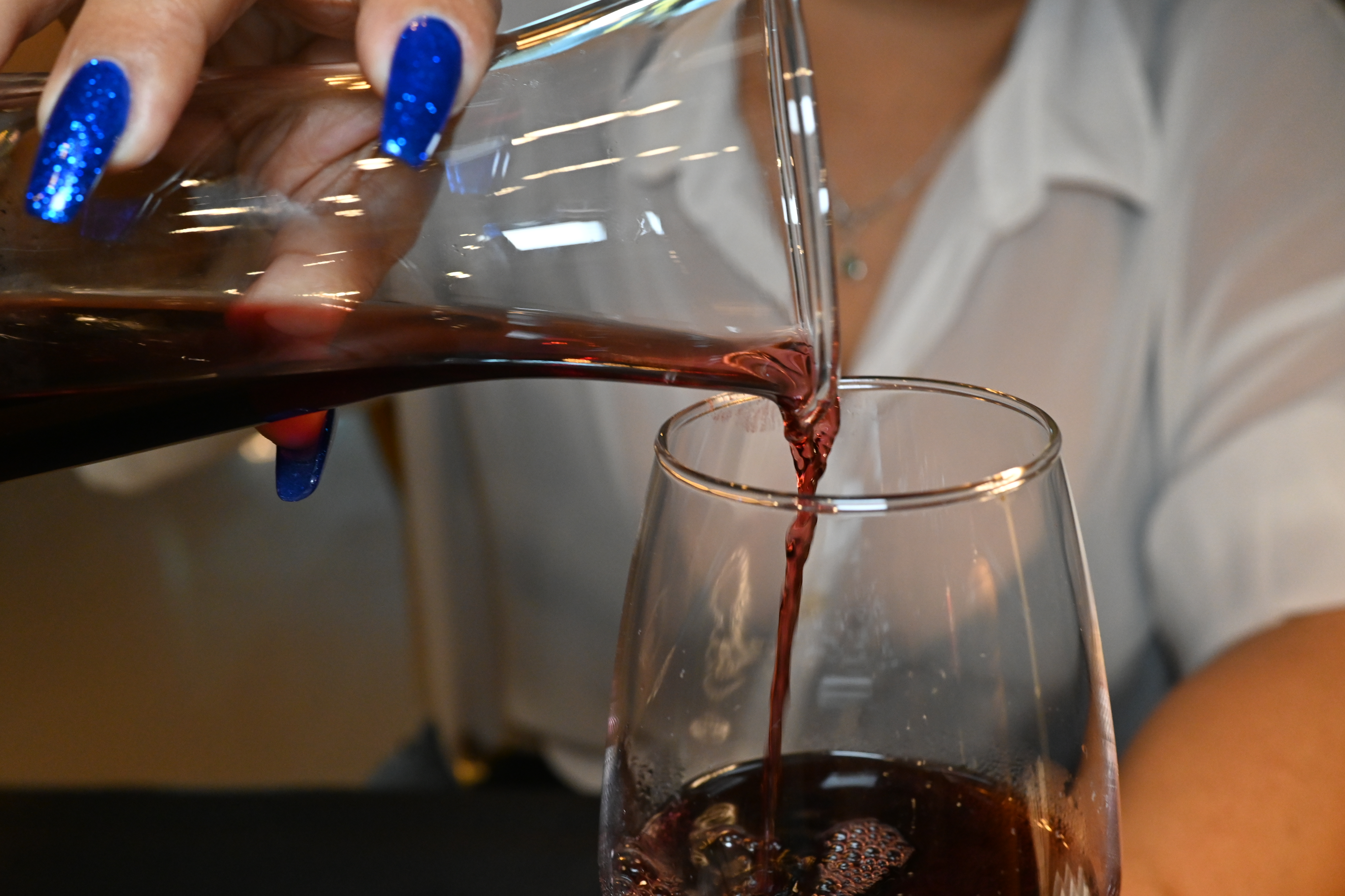 Red wine being poured from a glass carafe into a wine glass